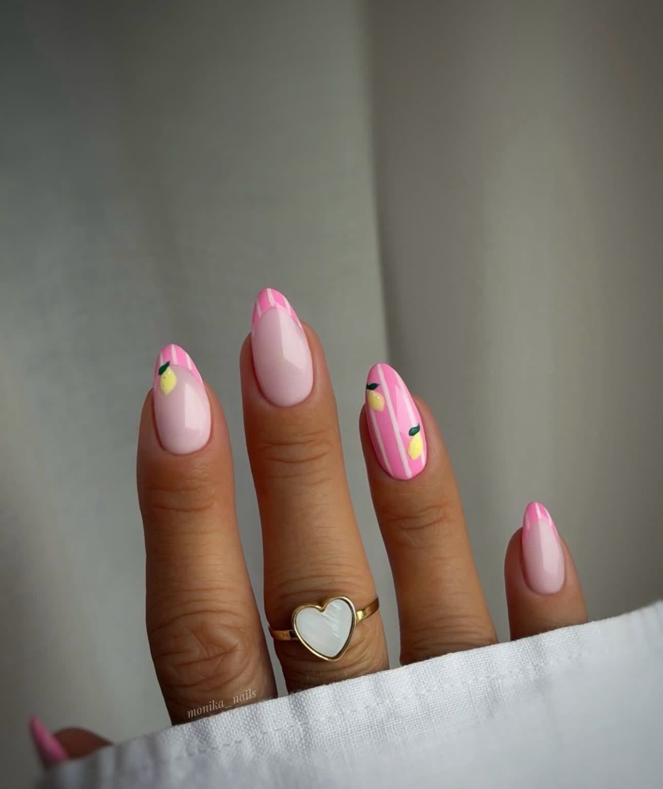 Main aux ongles en gel de forme amande : french rose, rayures et nail art citron peints à main levée.