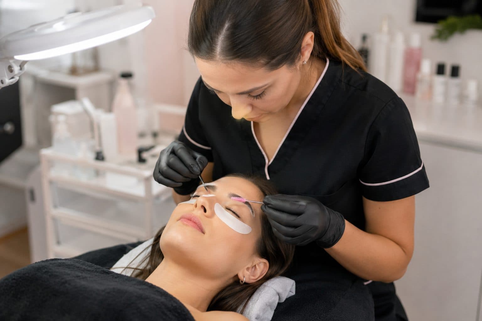 Brossage du sourcil à la spoolie pendant la séance, patch de protection sous l’œil : browlift et rehaussement dans la même journée.